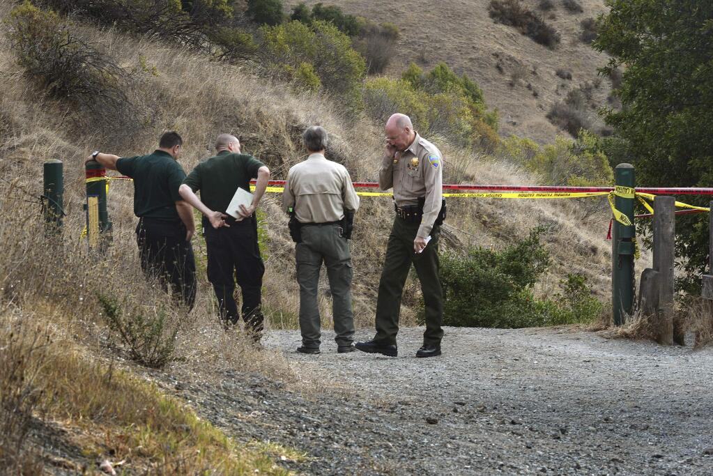 In this Tuesday, Oct. 6, 2015 photo, Marin County Sheriff's members investigate a homicide near the top of White's Hill on Old Railroad Grade near Fairfax, Calif. A tantra teacher who made DVDs on yoga for lovers and taught classes at a clothing-optional retreat was found shot to death on a hiking trail in Northern California, still holding onto the leash of his wounded dog, authorities said. Detectives are looking for three people of interest in the killing of Steve Carter, 67.(Robert Tong/Marin Independent Journal via AP)