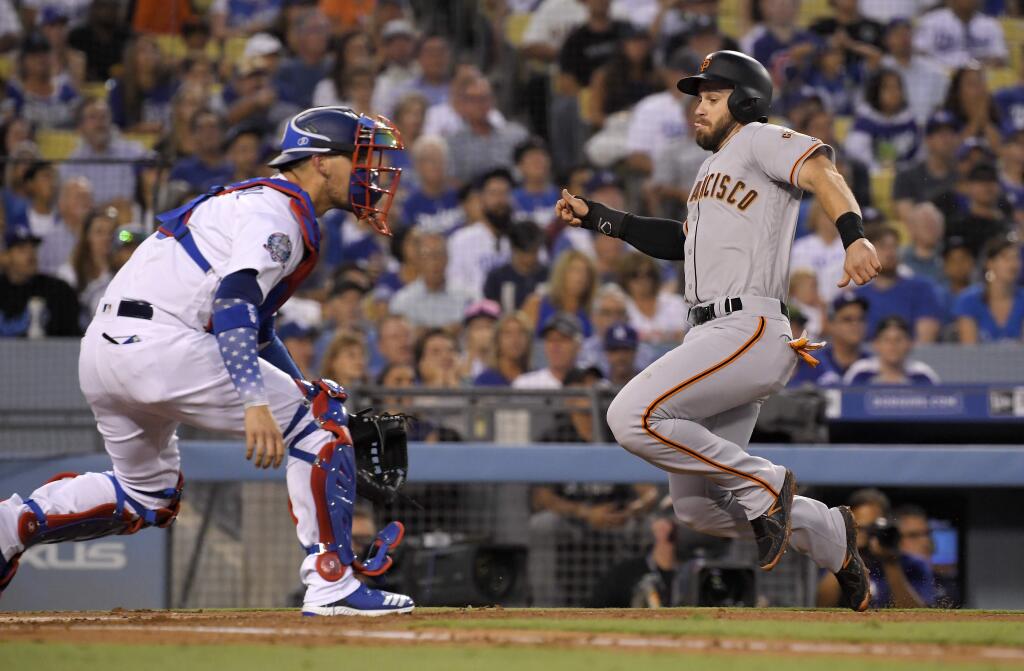 San Francisco Giants' Evan Longoria, right, scores on a single by Alen Hanson as Los Angeles Dodgers catcher Yasmani Grandal waits for the throw during the second inning of a baseball game Tuesday, Aug. 14, 2018, in Los Angeles. (AP Photo/Mark J. Terrill)
