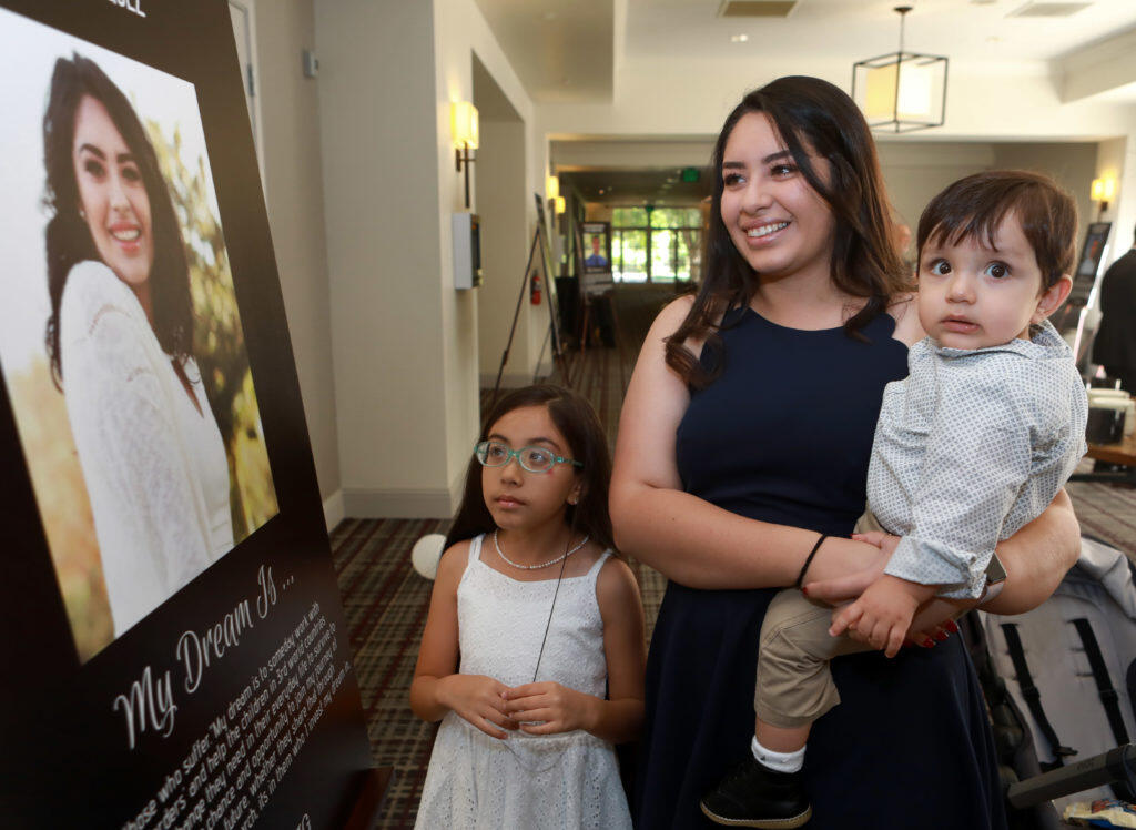 Angela Vazquez, a 2018 scholarship recipient, holds her brother, Cesar, 1, and Camila, 8, as they admire her poster during the Hispanic Chamber of Commerce Sonoma County’s Dream Big Scholarship Fund Gatsby Gala, 30th Anniversary benefit in Santa Rosa, on Saturday, June 30, 2018.  (Photo by Darryl Bush / For The Press Democrat)