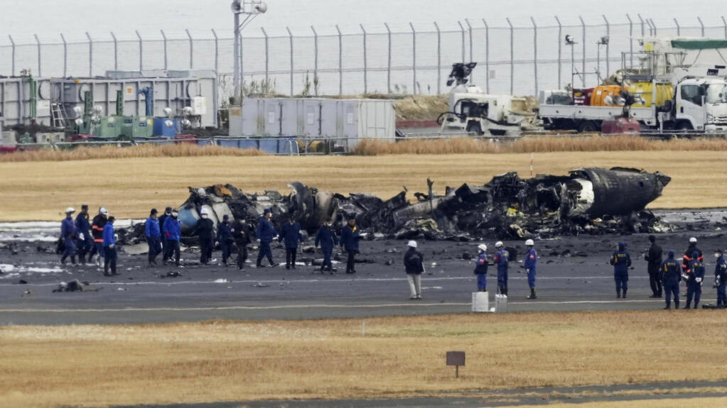 Police and Firefighters gather around the burn-out Japanese coast guard aircraft at Haneda airport on Wednesday, Jan. 3, 2024, in Tokyo, Japan. Transport officials and police each began their on site investigation at Tokyo’s Haneda Airport on Wednesday after a large passenger plane and the Japanese coast guard aircraft collided on the runway and burst into flames, killing several people aboard the coast guard plane. (Kyodo News via AP)