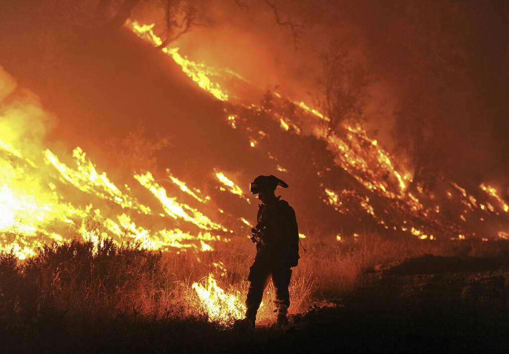 Cal Fire firefighter Bo Santiago observes a backfire as the Rocky fire burns near Clearlake in 2015. Photo by Josh Edelson, AP Photo