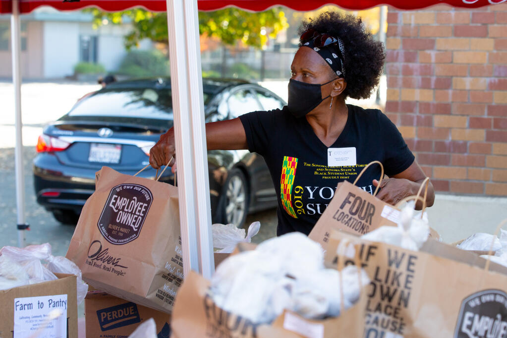 Sonoma County Black Forum board member Claudia de la Pena hands off bags of food to be given to recipients during a food distribution in Santa Rosa on Saturday, Nov. 21, 2020. (Alvin A.H. Jornada / The Press Democrat)
