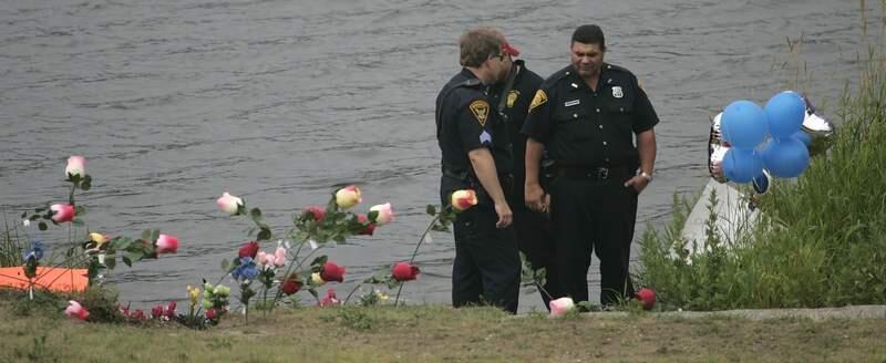 Bridgeport, Conn., police officers confer near memorial flowers and balloons at the edge of Bunnell Pond Thursday, July 5, 2007 in Bridgeport, Conn., where a van rolled into the water in Beardsley Park Wednesday. A mother, her son, and a family friend died in the van Wednesday. A nephew pulled from the van died Thursday. (AP Photo/Bob Child)