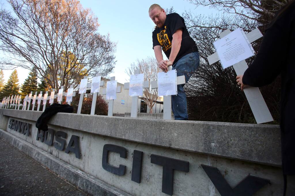 Forrest Schmidt places 56 crosses, said by protesters to represent the number of people who have died in officer-involved shootings in Sonoma County since 1995, in front of City Hall in Santa Rosa in 2013. (CHRISTOPHER CHUNG/ PD FILE)