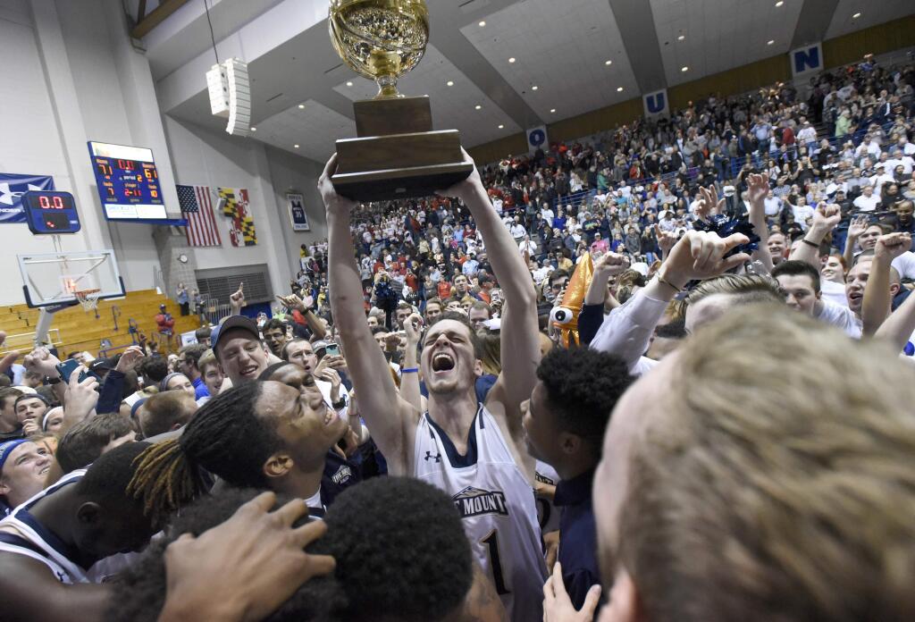 FILE - In this Tuesday, March 7, 2017, file photo, Mount St. Mary's forward Will Miller, center, celebrates with teammates after beating St. Francis (Pa.) 71-61 in the NCAA college basketball Northeast Conference Tournament championship, in Emmitsburg, Md. With the win, Mount St. Mary's earned an automatic berth to the NCAA Tournament. The 67-game March Madness basketball tournament begins Tuesday, March 14, with many games taking place during the work day. All of the games will be available online. For many of the early-round games, though, you'll need a password through your cable or satellite TV subscription. (AP Photo/Steve Ruark, File)