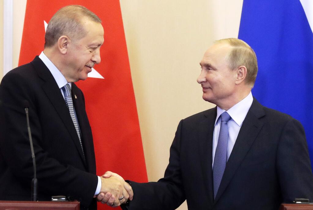 Turkish President Recep Tayyip Erdogan, left, and Russian President Vladimir Putin shake hands during a joint press conference with following their talks in the Bocharov Ruchei residence in the Black Sea resort of Sochi, Russia, Tuesday, Oct. 22, 2019. Erdogan says Turkey and Russia have reached a deal in which Syrian Kurdish fighters will move 30 kilometers (18 miles) away from a border area in northeast Syria within 150 hours. (Sergei Chirikov/Pool Photo via AP)