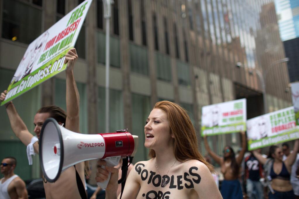 Rachel Jessee speaks into a megaphone while riding atop a car during the GoTopless Day Parade, Sunday, Aug. 23, 2015, in New York. (AP Photo/Kevin Hagen)