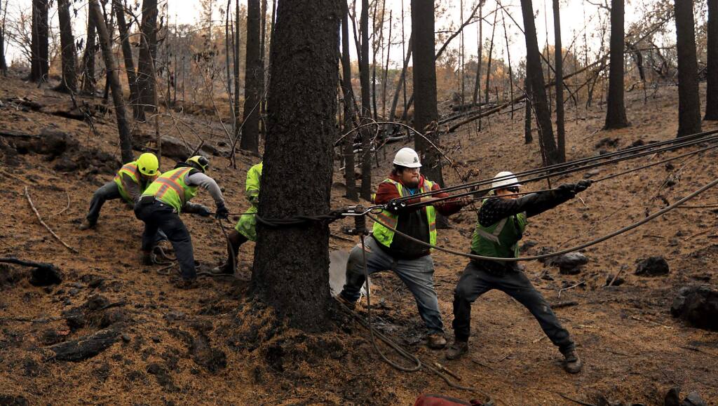 A tree removal crew from CORE of Corona, Ca., use a winch system to help take town burned trees on the Matula property in Kenwood, Wednesday Nov. 15, 2017. (Kent Porter / Press Democrat) 2017