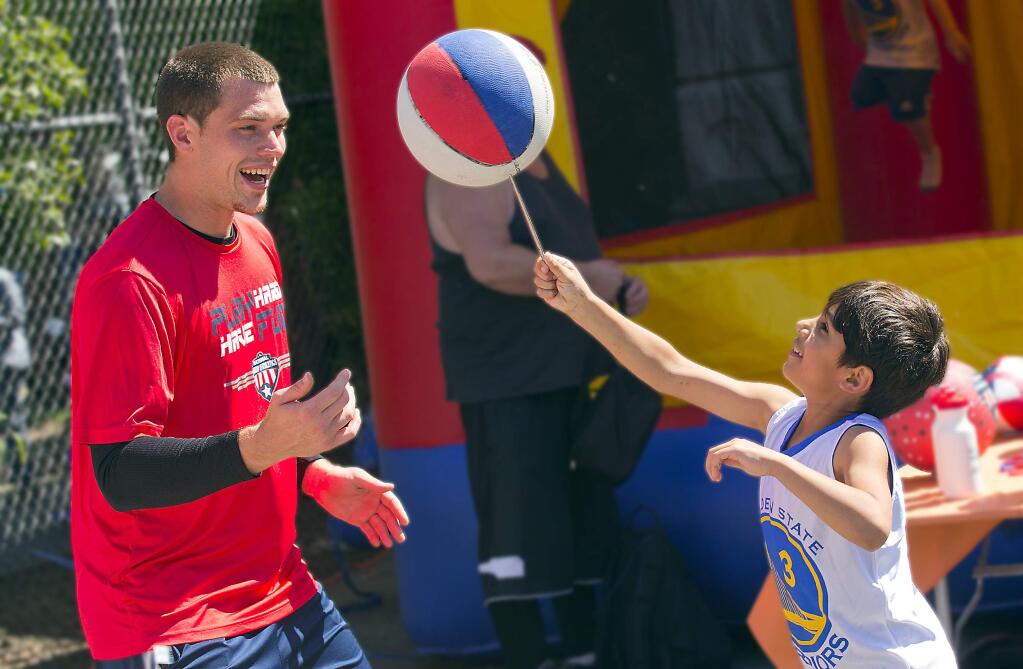 Sam Kruk, with the National Academy of Athletics encourages Gavin Barrera, 7, to keep a basketball spinning at the Healthy Kids Day event and the Sonoma County Family YMCA in Santa Rosa on Saturday. (photo by John Burgess/The Press Democrat)