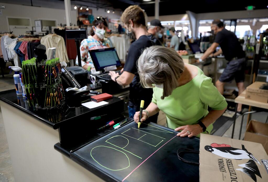 Patti Davi of Sonoma Outfitters paints a sandwich board to place in front of the Montgomery Village store, Saturday, June 6, 2020 in Santa Rosa. (Kent Porter / The Press Democrat) 2020