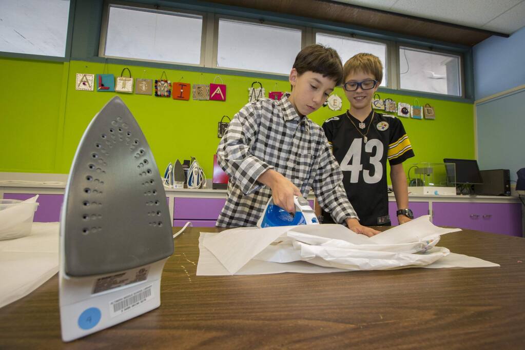 Seventh graders Lucas Stevenson and Thomas Griego in the new maker lab at Altimira Middle School. The heat from the iron welds several plastic bags together into a 'fabric' that can be used to make almost anything. (Photo by Robbi Pengelly/Index-Tribune)