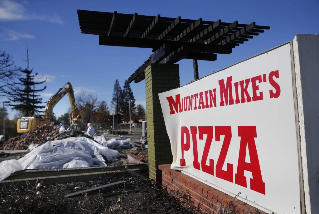 Employees of Excel Site Services clean up burned debris at Mountain Mike's Pizza on Cleveland Avenue on Wednesday, Nov. 29, 2017 in Santa Rosa. (BETH SCHLANKER/ PD)