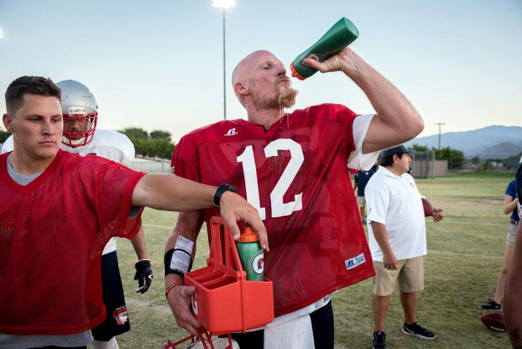 Todd Marinovich (12) with backup quarterback Michael Karls, during practice with the SoCal Coyotes in Indio, Calif., on Aug. 22, 2017. Marinovich, who entered the national spotlight as a high school standout and later encountered addiction problems, is the 48-year-old starting quarterback for the World Developmental League team. (Michael Ares/The New York Times)