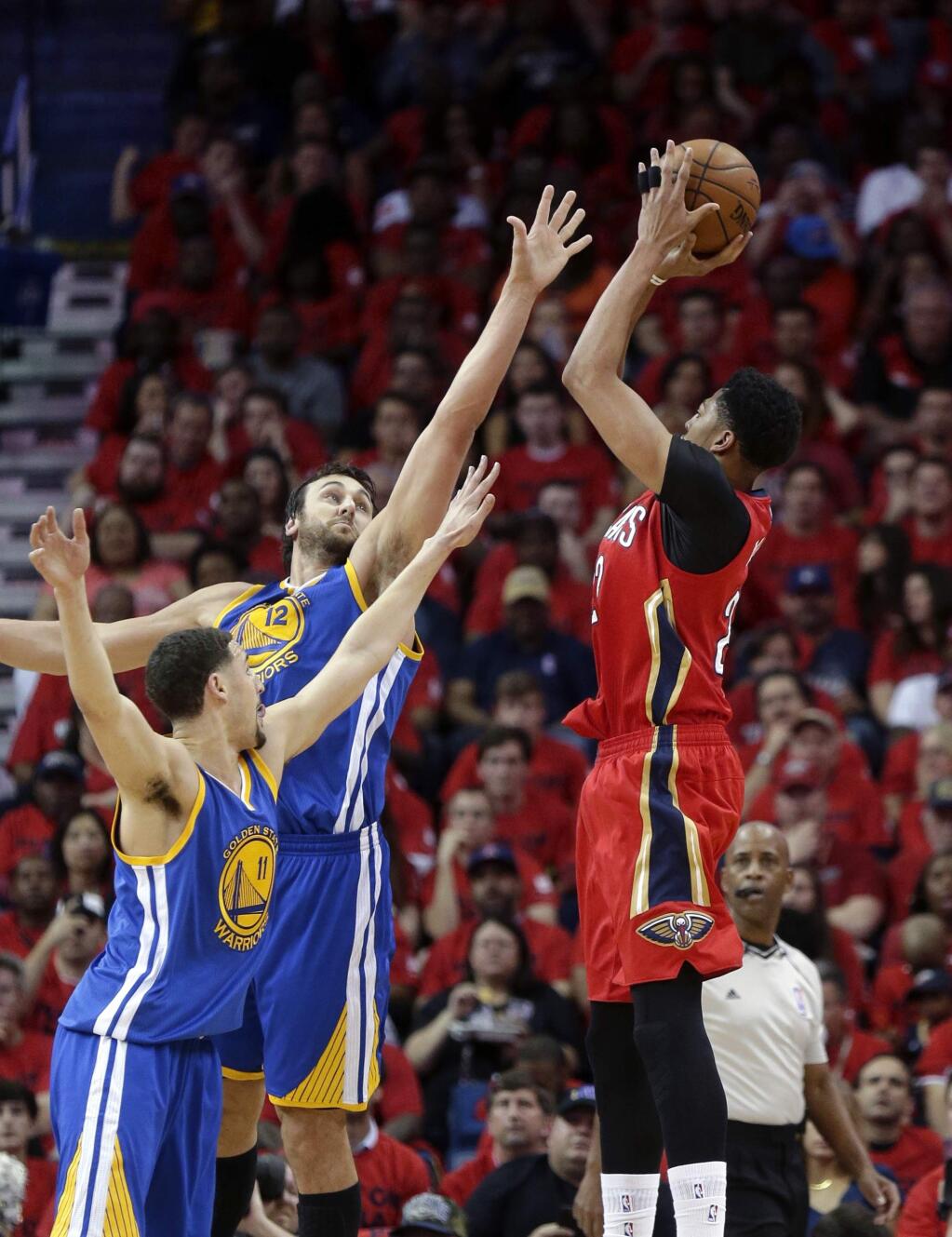 New Orleans Pelicans forward Anthony Davis (23) shoots against Golden State Warriors center Andrew Bogut and guard Klay Thompson, bottom left, during the first half of Game 3 of a first-round NBA basketball playoff series Thursday, April 23, 2015, in New Orleans. (AP Photo/Gerald Herbert)