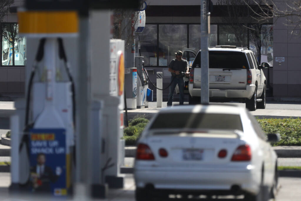 A man fills up his tank at the Chevron gas station located across the street from a Shell gas station at the intersection of Lakeville St. and Caulfield Lanes in Petaluma, Calif., on Thursday, March 4, 2021. (Beth Schlanker/ The Press Democrat)