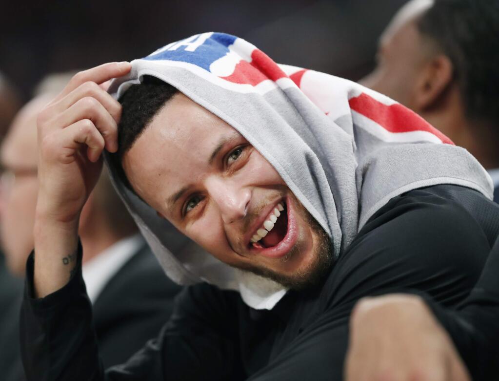 Golden State Warriors guard Stephen Curry, his head covered by a towel, laughs with teammates during the second half against the New York Knicks, Monday, Feb. 26, 2018, in New York. (AP Photo/Kathy Willens)