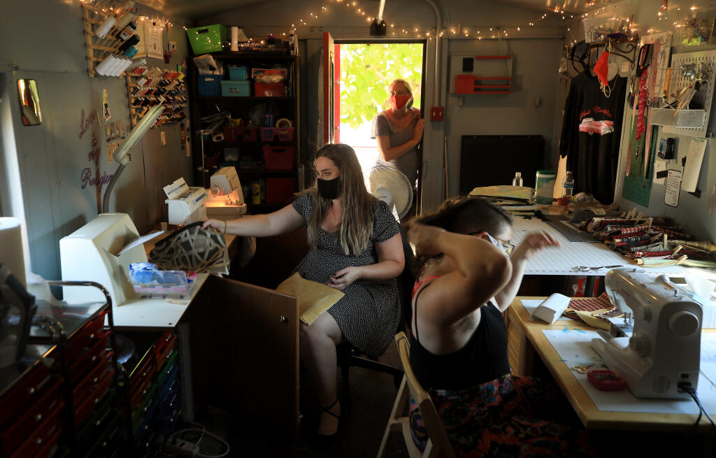 Alyssa Long, left, and Kaitlin Pederson prepare to sew art bags for Windsor students, Monday, August 10, 2020 in Santa Rosa that are designed to hold art supplies.  In the doorway is Long's sister Taylor LaFranchi.  (Kent Porter / The Press Democrat) 2020