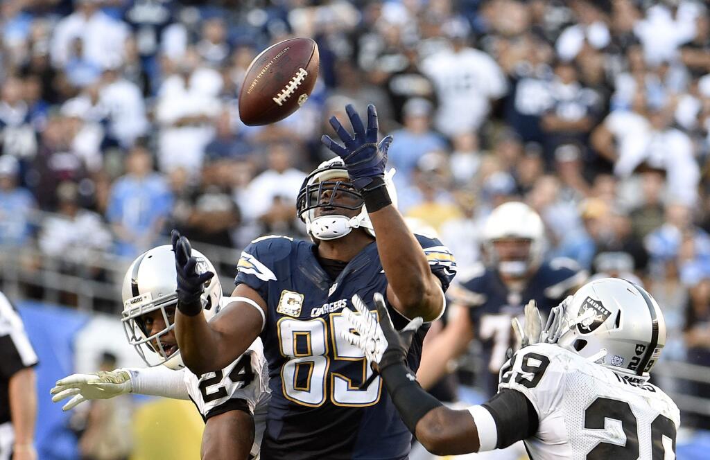 San Diego Chargers tight end Antonio Gates (85) makes a pass reception between Oakland Raiders free safety Charles Woodson (24) and strong safety Brandian Ross (29) during the fourth quarter of an NFL football game Sunday, Nov. 16, 2014, in San Diego. (AP Photo/Denis Poroy)