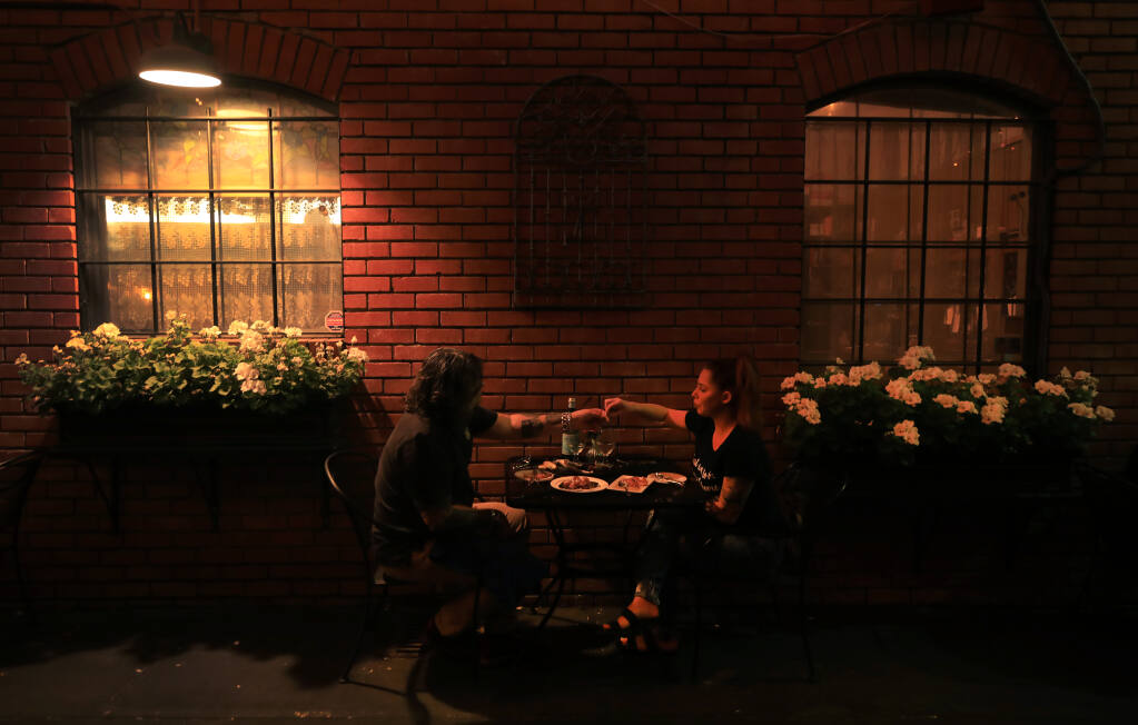 George and Arielle Szorenyi of Orange County share a quiet moment at La Gare French Restaurant, Friday, Sept. 18, 2020 in Santa Rosa, which moved their dining to the alleyway adjacent to the establishment due to the pandemic. (Kent Porter / The Press Democrat) 2020