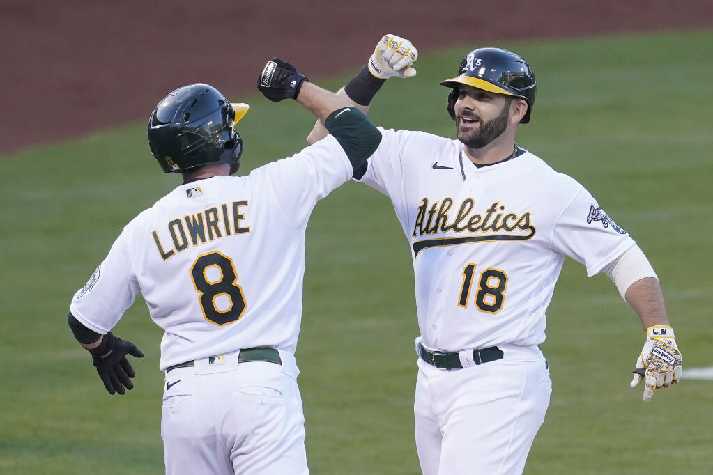 The Oakland Athletics’ Mitch Moreland, right, celebrates after hitting a two-run home run that scored Jed Lowrie during the second inning against the Toronto Blue Jays in Oakland on Tuesday, May 4, 2021. (Jeff Chiu / ASSOCIATED PRESS)