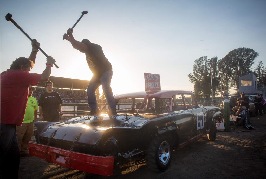 Ralph and Pedro Garcia hammer a crease in the backend of their car before the start of the destruction derby at the 2015 Sonoma County Fair in Santa Rosa, Calif. Saturday, August 1, 2015.