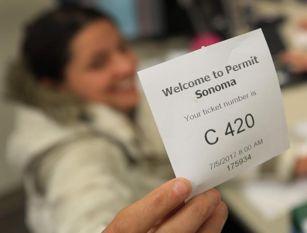 Karen Kohley of Santa Rosa's Flora Cal Farms was the first in line and received the first ticket - 420 - Wednesday July 5, 2017 as she submits her permit for her marijuana business at the Sonoma County Permit and Resource Management Department in Santa Rosa. (Kent Porter / Press Democrat) 2017