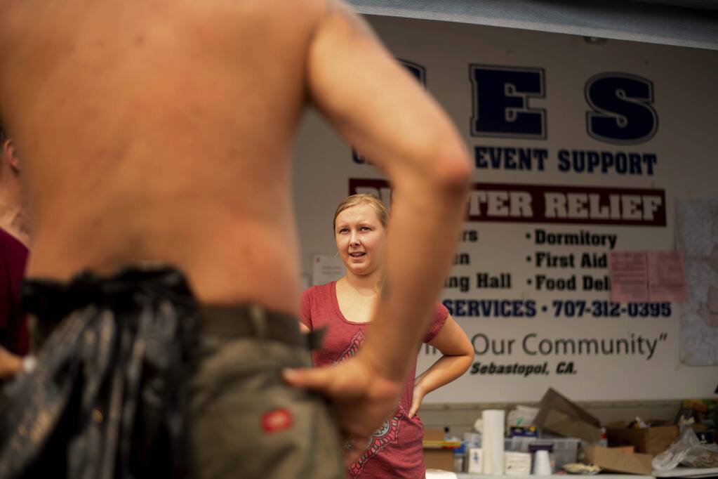 Volunteer Alexis Rogers helps a man obtain supplies at a makeshift shelter for Mendocino Complex Fire evacuees on Wednesday, Aug. 8, 2018, in Clearlake, Calif. (AP Photo/Noah Berger)