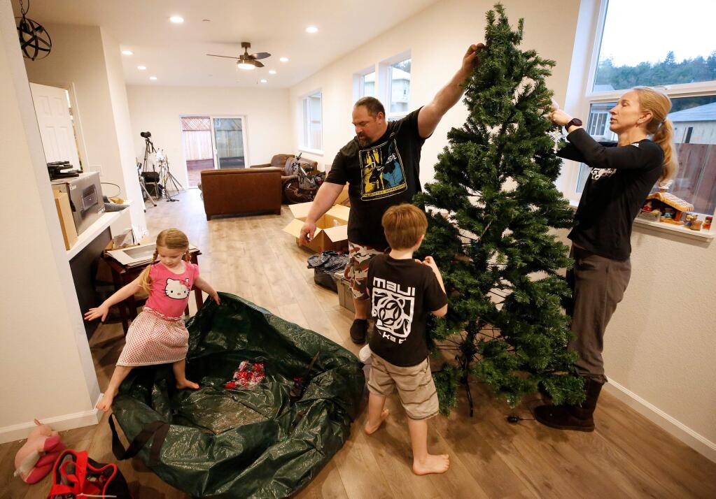 Fire survivors Chris Keys, center, his wife Sara and their children Isaac, 6, and Emma, 3, assemble their family Christmas tree as they move into their rebuilt home in the Hidden Valley neighborhood of Santa Rosa, California, on Friday, December 13, 2019. (Alvin Jornada / The Press Democrat)