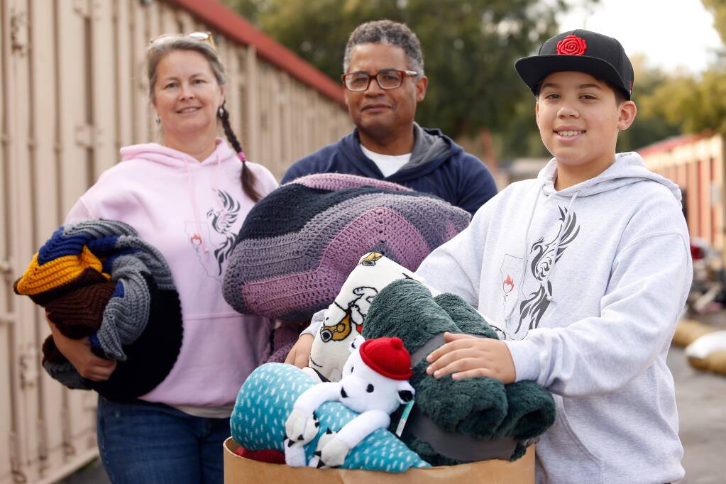Ian Rich, 13, right, founder of Operation Blanket, which collects new blankets and gives them to homeless families, with his parents Cary and Josiah, in Santa Rosa, California on Saturday, November 25, 2017. The mission of Ian Rich's Operation Blanket has given him and his family a new sense of purpose after their own home was destroyed in the Tubbs Fire. (Alvin Jornada / The Press Democrat)