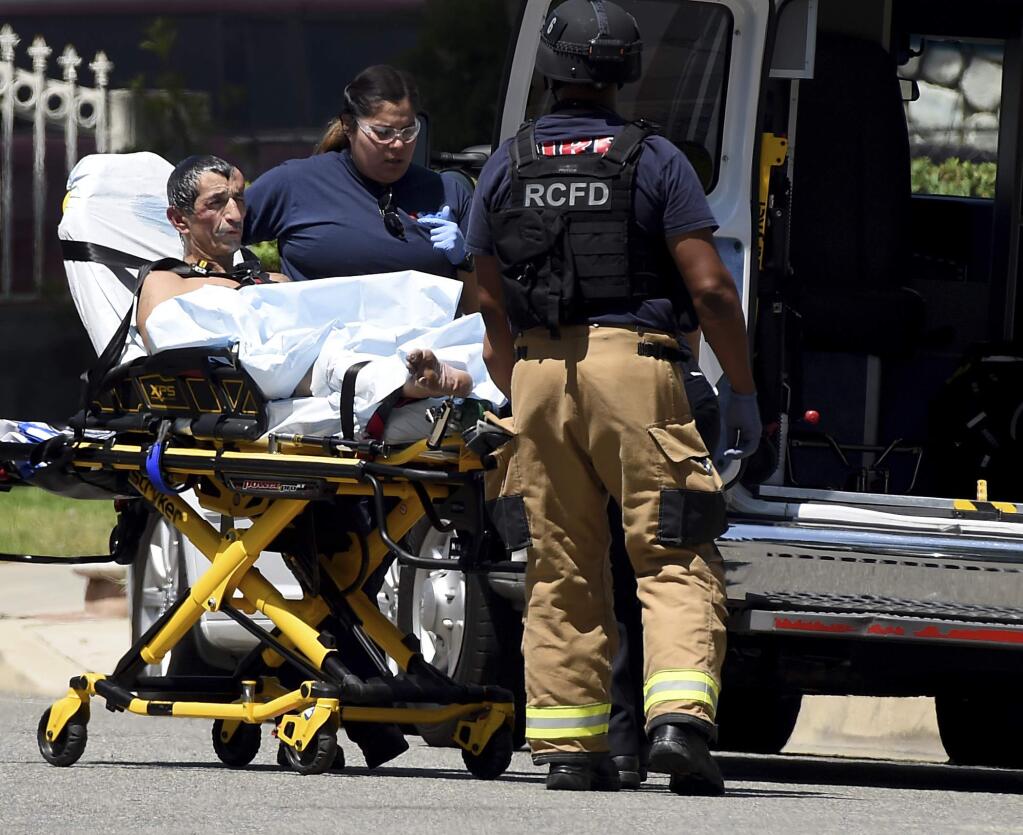 Suspect Gilbert Banuelos, 54, is taken to an ambulance after ending a barricade in the 13000 block of Vine Street in Rancho Cucamonga on Monday, Aug. 19, 2019. Banuelos was taken into custody after allegedly setting his mother on fire and then barricading himself in the home for hours. (Jennifer Cappuccio Maher/The Orange County Register via AP)