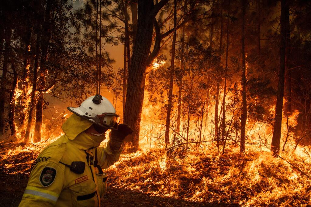 In an effort to create a fire break, volunteer firefighters tend a controlled burn along Princess Highway in Australia's Meroo National Park, Jan. 5, 2020. With thousands fleeing eastern towns this weekend as fires swept from the hills to the coast in Australia, the inescapable realities of a warming world were colliding with the calculated politics of inaction. (Matthew Abbott/The New York Times)