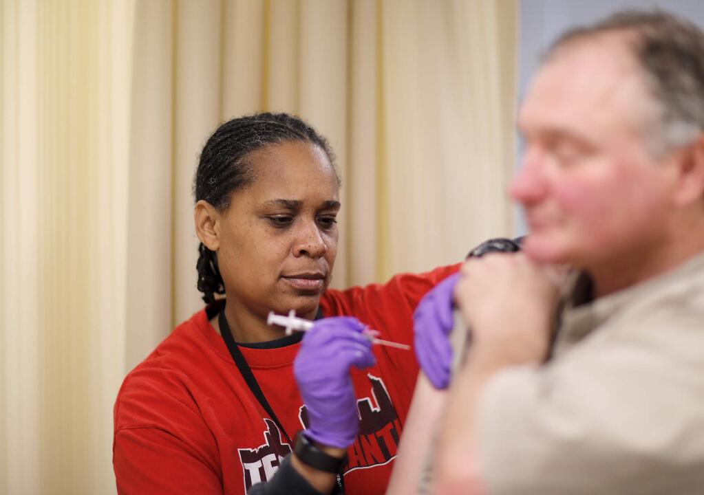 Scott Turner, right, gets a flu shot from nurse Nicole Simpson at the Salvation Army in Atlanta, Wednesday, Feb. 7, 2018. The U.S. government's latest flu report released on Friday, Feb. 2, 2018, showed flu season continued to intensify the previous week, with high volumes of flu-related patient traffic in 42 states, up from 39 the week before. (AP Photo/David Goldman)