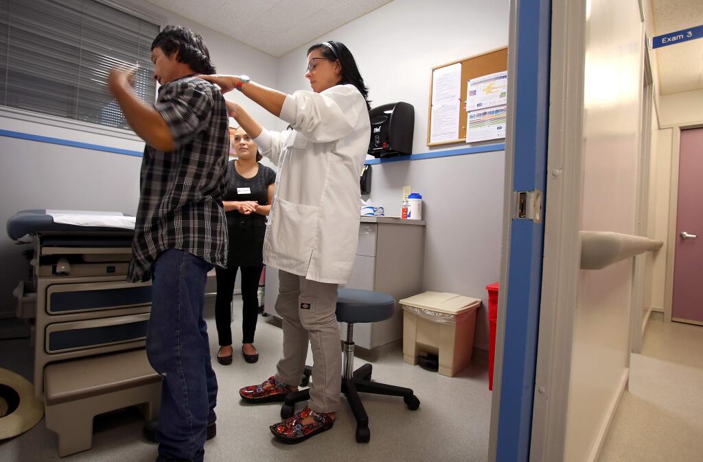 Family nurse practitioner Kathy Kladar, right, examines patient Eleazar Gonzalez Sandoval, while medical assistant Tania Morales helps with translating, at the Jewish Community Free Clinic, in Santa Rosa on Thursday, September 11, 2014. (Christopher Chung/ The Press Democrat)