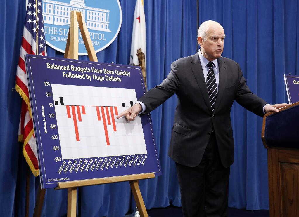 California Gov. Jerry Brown gestures to a chart show balanced budgets are followed by large budget deficits while discussing his $124 billion revised state budget plan, Thursday, May 11, 2017, in Sacramento, Calif. (AP Photo/Rich Pedroncelli)