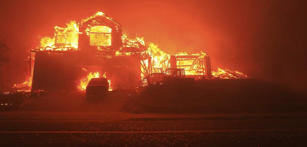 FILE - In this Oct. 9, 2017, file photo, a home burns in Fountaingrove in Santa Rosa, Calif. Police body-camera footage from 2017's wildfires in California's wine country shows officers running door-to-door urging people to flee and rescuing elderly residents of a retirement community as flames bear down. Video obtained by the San Jose Mercury News is from the point-of-view of police in Santa Rosa, as they sprint through swirling smoke amid the firestorm. (Kent Porter/The Press Democrat via AP, File)