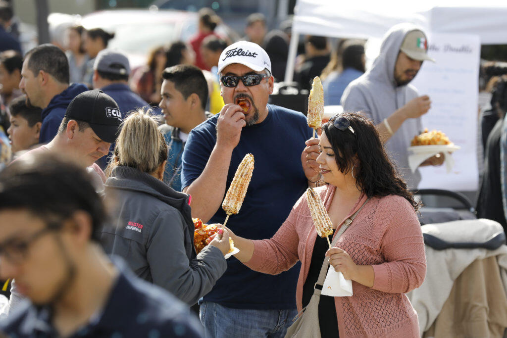 (From left)Ana Perez, her husband,Javier, sister-in-law Xochitl Chavez, and brother Jorge Chavez eat elote, Mexican grilled corn, and chips during the Cinco de Mayo celebration at the Roseland Village Shopping Center in Santa Rosa on Sunday, May 5, 2019. (BETH SCHLANKER/ The Press Democrat)