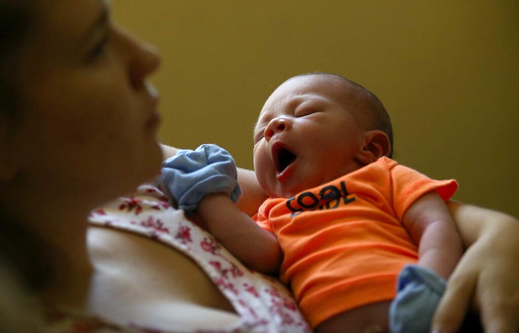 Alexander Flores, 2 weeks, yawns while his mother Andrea signs up for a new mothers class at the Women, Infants, Children office (WIC) on Wednesday afternoon. (JOHN BURGESS / The Press Democrat)