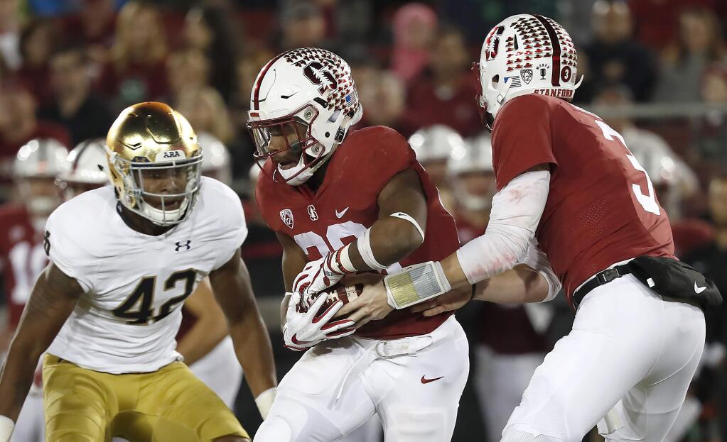 In this Nov. 25, 2017, file photo, Stanford quarterback K.J. Costello (3) hands off to Stanford running back Bryce Love (20) against Notre Dame during the first half in Stanford. (AP Photo/Tony Avelar, File)