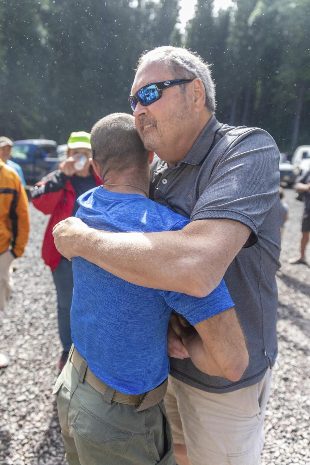 John Eller, right, hugs rescue lead Javier Cantellops at the Makawao Forest Reserve base camp on Saturday, May 25, 2019 in Wailuku, Maui. The Maui News reported Friday Amanda Eller was found injured in the Makawao Forest Reserve. Family spokeswoman Sarah Haynes confirmed she spoke with Eller's father John. Eller was airlifted to safety. (Bryan Berkowitz/Honolulu Star-Advertiser via AP)