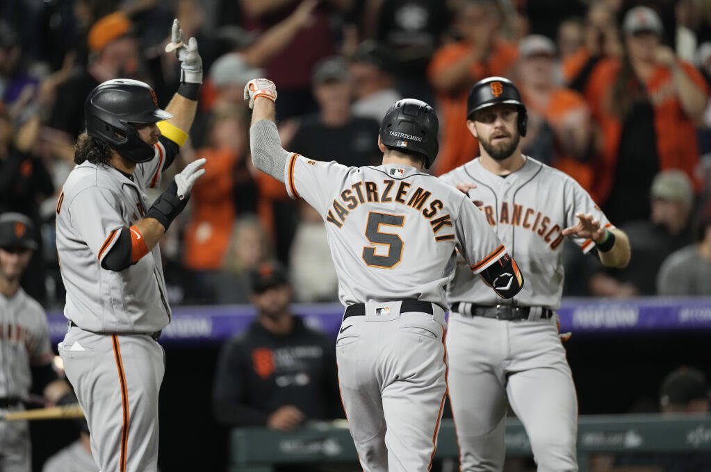 The San Francisco Giants’ Mike Yastrzemski, center, is congratulated by Brandon Crawford, left, and Evan Longoria after Yastrzemski hit a three-run home run off Colorado Rockies relief pitcher Ashton Goudeau in the seventh inning on Friday, Sept. 24, 2021, in Denver. (David Zalubowski / ASSOCIATED PRESS)