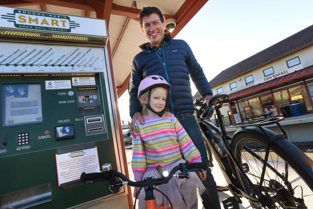 Phil Mooney, 35, and his 4-year-old daughter, Tillie, at SMART’s downtown San Rafael station, on Friday, Dec. 18, 2020. The geology instructor at Sonoma State University and former pro cyclist is also a vocal advocate for the completion of the planned 70-mile multiuse pathway along the SMART line. (Erik Castro / for The Press Democrat)