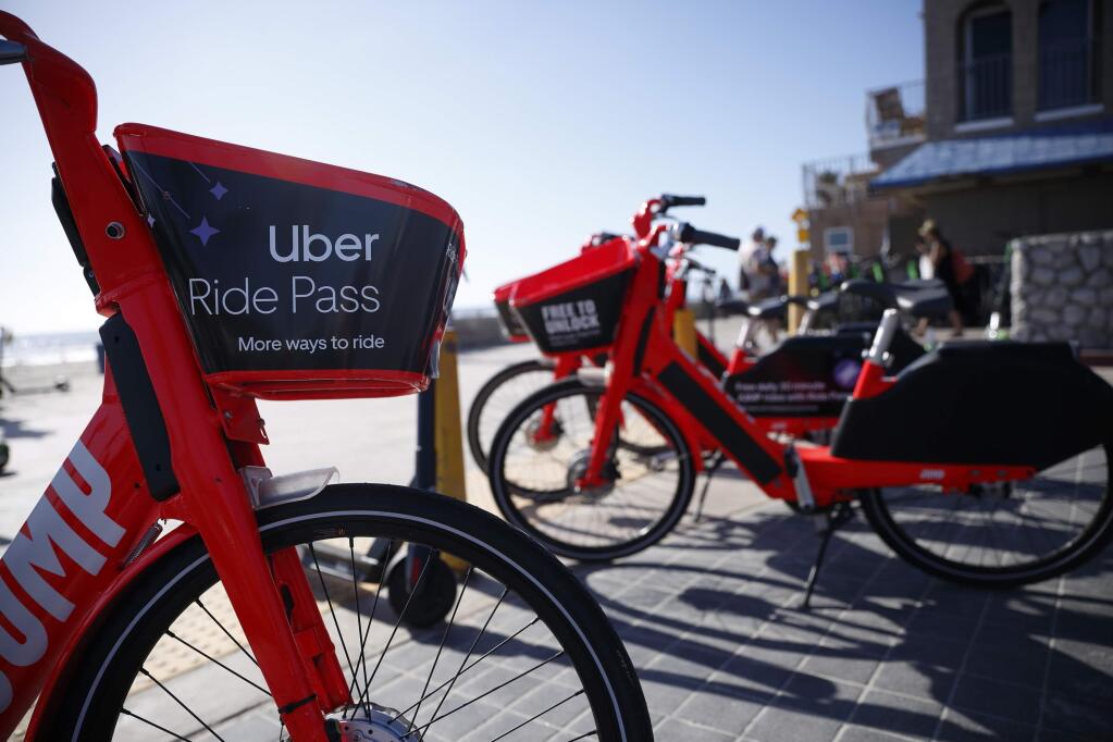 FILE - In this May 28, 2019, file photo Jump electric bike share bicycles by Uber are seen along Mission Beach boardwalk in San Diego. Uber reports financial results Thursday, Aug. 8. (AP Photo/Gregory Bull, File)