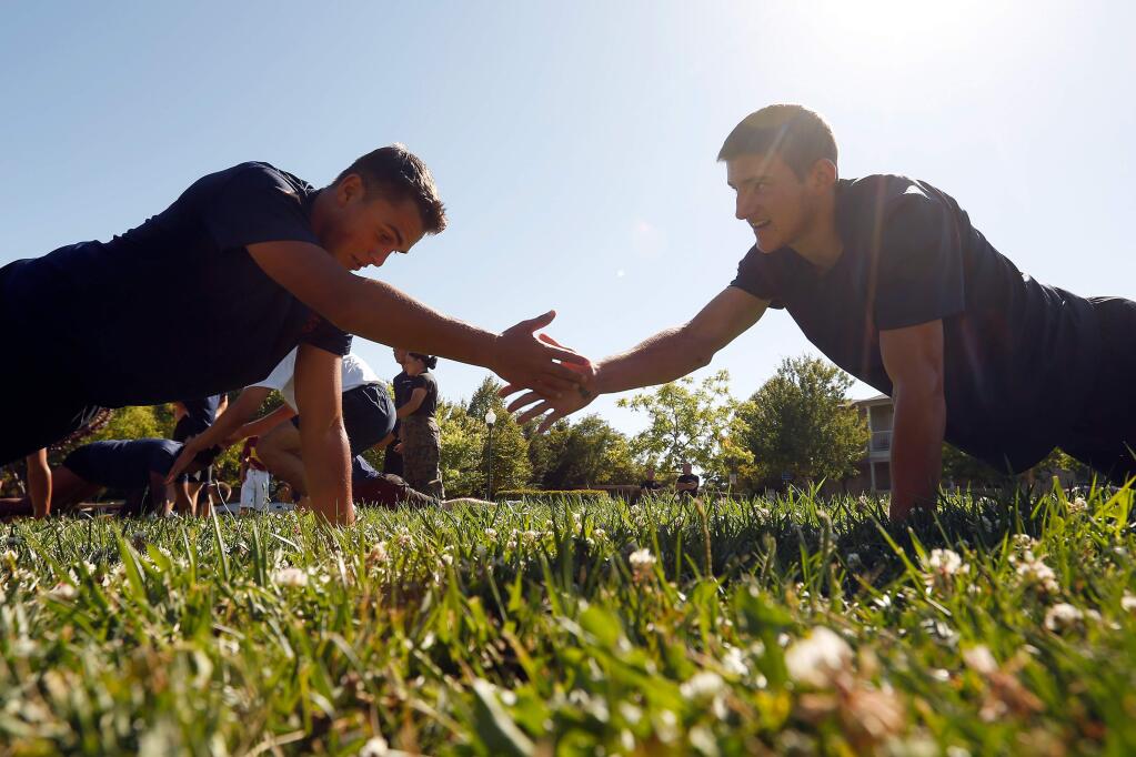 Marine Corps enlistees, or poolees Keaone Stephens, left, and Tyler Cato, who graduated from Montgomery High School together, perform buddy push ups during a physical training session with Marine recruiters and other poolees at Harvest Park in Santa Rosa, California, on Wednesday, August 1, 2018. (Alvin Jornada / The Press Democrat)