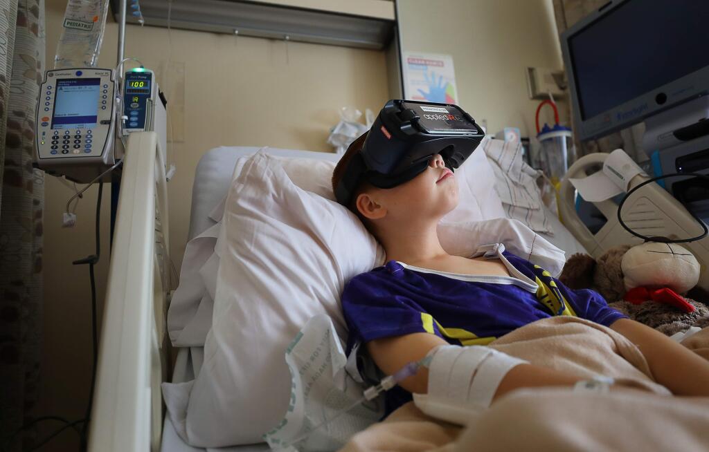 Santa Rosa Memorial Hospital pediatrics patient Andre Slack, 9, relaxes by watching dolphins swim in a virtual reality headset on Friday, August 9, 2019. (Christopher Chung/ The Press Democrat)