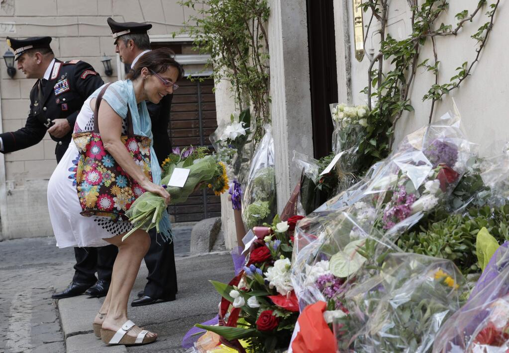 A woman leaves flowers in front of the Carabinieri station where Mario Cerciello Rega was based, in Rome, Saturday, July 27, 2019. In a statement Saturday, Carabinieri officers investigating the death Friday of officer Cerciello Rega, 35, said two American turists, both 19, have been detained for alleged murder and attempted extortion. (AP Photo/Andrew Medichini)
