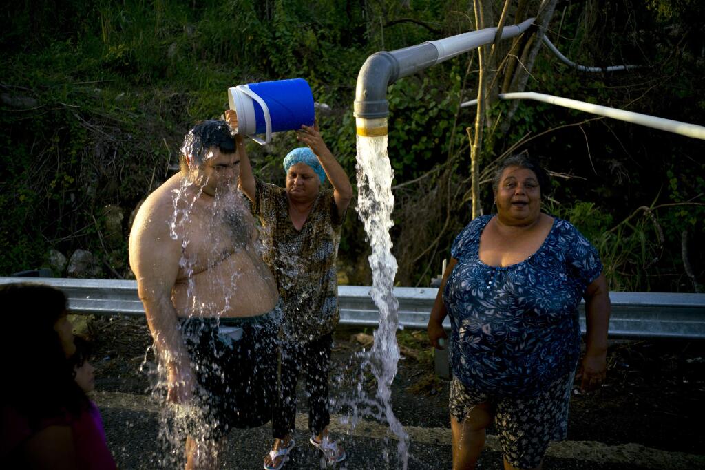 FILE - In this Oct. 14 2017 file photo, residents bathe in water piped from a mountain creek in Utuado, Puerto Rico. A month after Hurricane Maria made landfall, hundreds of thousands of people are still without running water, and almost half of the island's sewage treatment plants are out of service. (AP Photo/Ramon Espinosa, File)