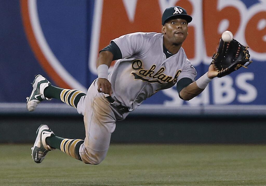Oakland Athletics left fielder Khris Davis dives to catch a fly by hit by the Los Angeles Angels' Jett Bandy during the sixth inning in Anaheim, Friday, June 24, 2016. (AP Photo/Alex Gallardo)