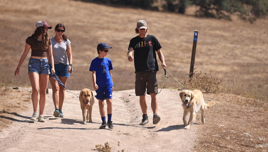 From left, Juniper Brand, 14, Megan Suarez, Koah Brand, 10, and Jason Brand, take their dogs Charlie and Messi for a walk at Taylor Mountain Regional Park in Santa Rosa, Monday, Sept. 6, 2021.  The family, evacuated from Meyers and the Caldor fire, took a hike in the relatively clean air as opposed to what they evacuated from.  (Kent Porter / The Press Democrat)