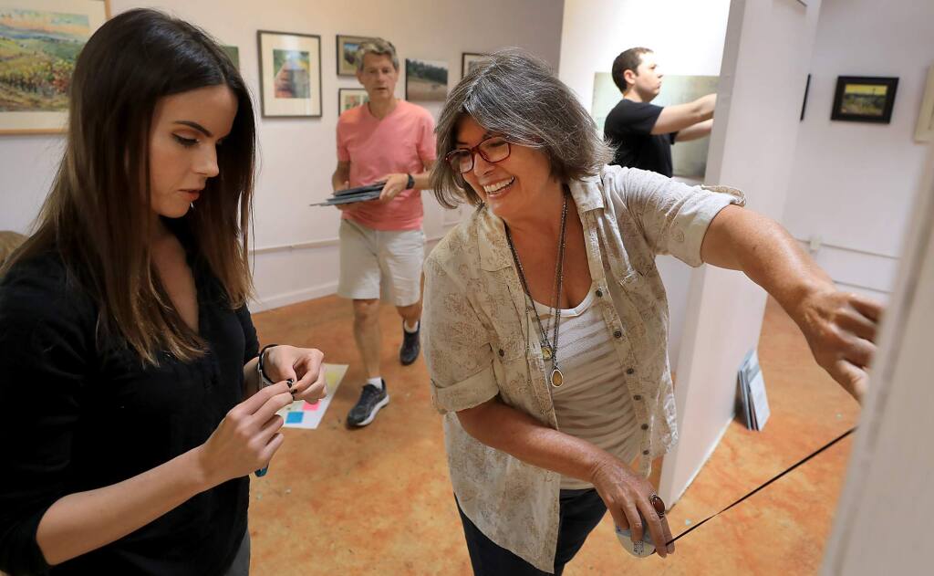 Sonoma State University anthropologist Dr. Margaret Purser, right and SSU student Hannah Bowman of Santa Rosa, hang an exhibit 'Highway 101 in the Neighborhood' at the Santa Rosa Arts Center on South A Street. Purser is leading the creation of an online Santa Rosa Neighborhood Heritage Mapping Project, Friday, July 13, 2018. (Kent Porter / The Press Democrat) 2018