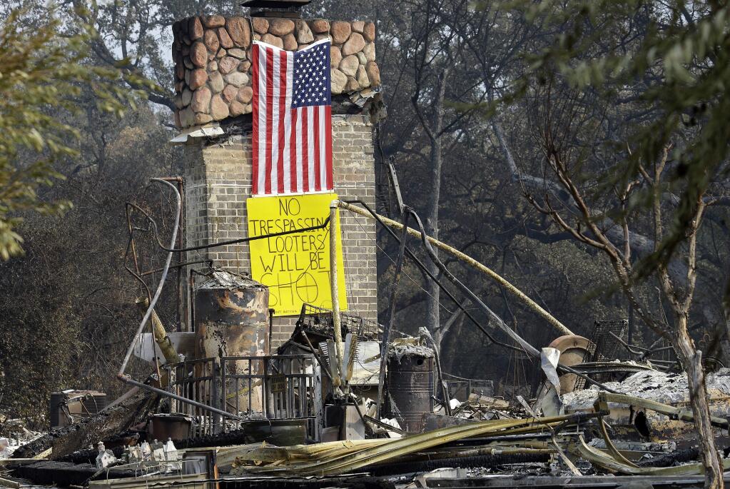 A sign warning looters will be shot is seen on the chimney of a home destroyed by wildfires on Wednesday, Oct. 18, 2017, in Glen Ellen, Calif. (AP Photo/Ben Margot)